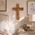 Wooden cross on a wall above a dresser with decorative items in a bedroom setting.