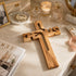 Wooden cross on a marble surface with a magazine and decorative items.