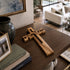 Wooden cross on a table with books and a vase in a living room setting