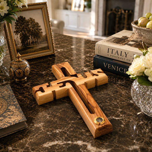 Wooden cross on a marble surface with books and decorative items in the background