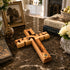 Wooden cross on a marble surface with books and decorative items in the background