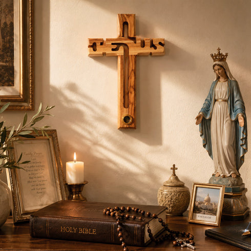 Wooden cross, statue of a religious figure, candle, and Bible on a wooden surface.