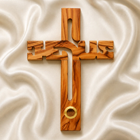 A Jesus-shaped olive wood cross with holy soil from Jerusalem, featuring detailed carvings and an embedded ring for holding holy soil.