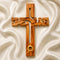 A Jesus-shaped olive wood cross with holy soil from Jerusalem, featuring detailed carvings and an embedded ring for holding holy soil.