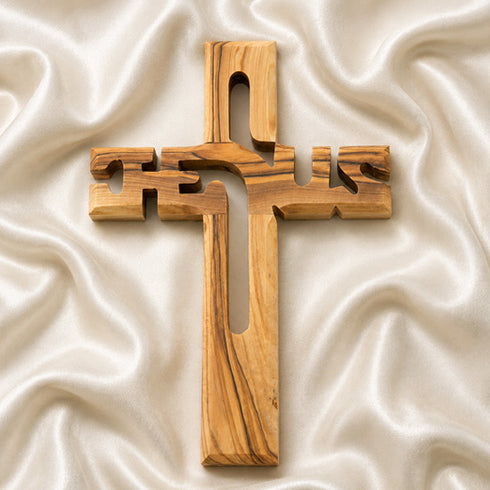 Wooden cross on a textured white fabric background