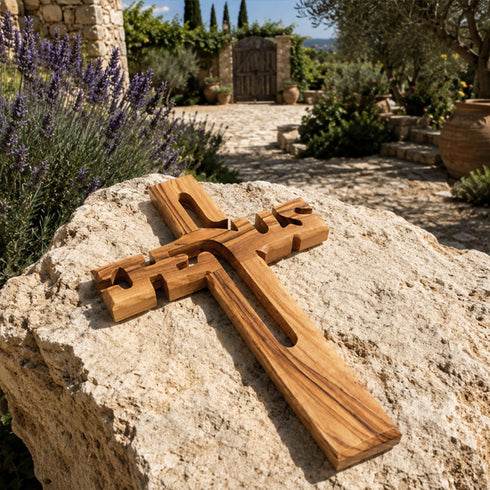 Wooden cross on a rock with a garden and stone wall in the background