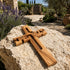 Wooden cross on a rock with a garden and stone wall in the background