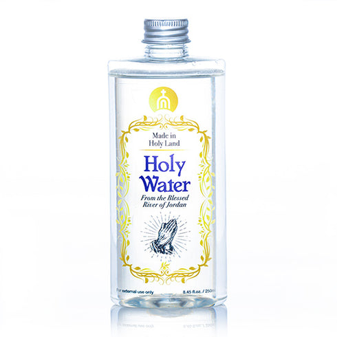 A clear plastic bottle containing Holy Water from the Blessed River of Jordan, with a metal cap and a label featuring gold, blue and black text, and a graphic symbol.
