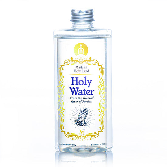 A clear plastic bottle containing Holy Water from the Blessed River of Jordan, with a metal cap and a label featuring gold, blue and black text, and a graphic symbol.