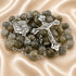 A rosary with gray and green labradorite beads, a crucifix, and a small medal pendant, on a beige satin fabric background.