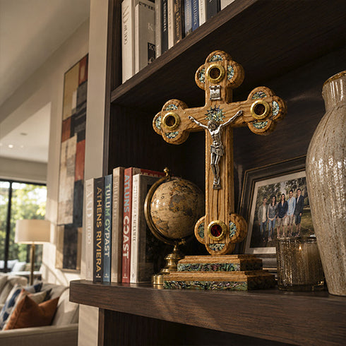 Decorative cross on a bookshelf with books and a vase in a home setting