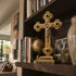 Decorative cross on a bookshelf with books and a vase in a home setting