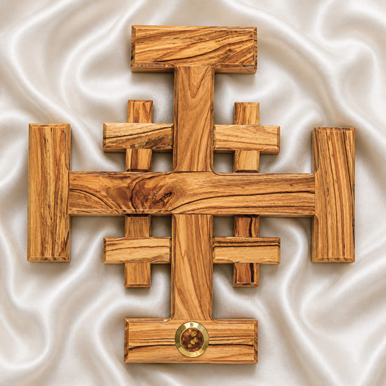 Top view of a large olive wood Crusader Cross on white satin cloth