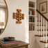 Jerusalem cross on a wall next to a mirror and staircase