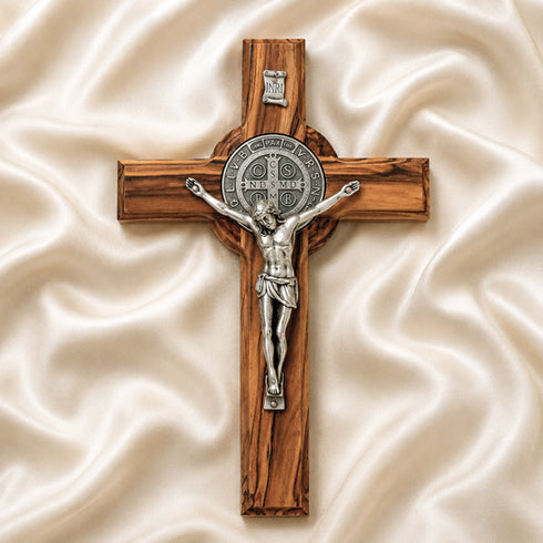 Wooden cross with silver Jesus figure on a beige fabric background