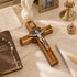 Wooden cross with silver Jesus figure on a marble surface with religious items.