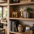 Wooden bookshelf with decorative items including a cross, books, and vases in a living room setting.