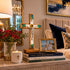 Decorative setup on a console table with books, cross, candle, and framed photo.