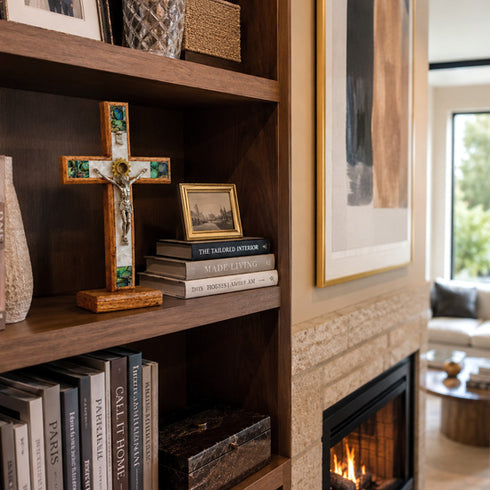 Bookshelf with books, a cross, and framed pictures in a living room with a fireplace.