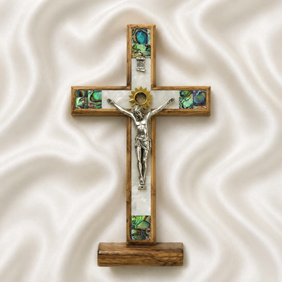 Wooden cross with a figurine of Jesus on a white fabric background