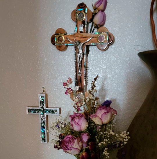 Olive wood eastern cross hanging on a wall, Crucifix and INRI plaque with Four Elements next to a Nacre Latin cross.