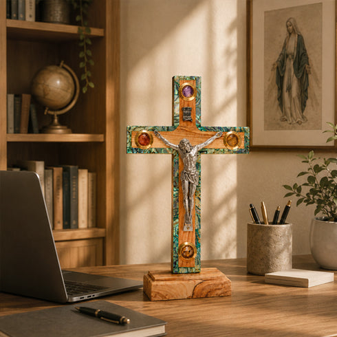 Decorative cross on a desk with a laptop and books in the background
