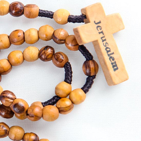 Close-up image of a Latin-style cross with Jerusalem written on it on a handcrafted olive wood rosary.