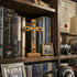 Wooden latin cross with Jesus corpus on a bookshelf with medical books and personal photos.