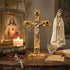 Wooden cross with Jesus Christ figure, candle, Bible, rosary, and religious statues on a table.