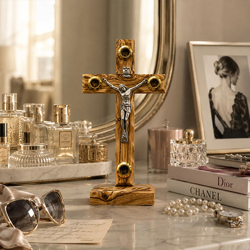 Wooden latin crucifix with corpus on a table with sunglasses, books, and jewelry.