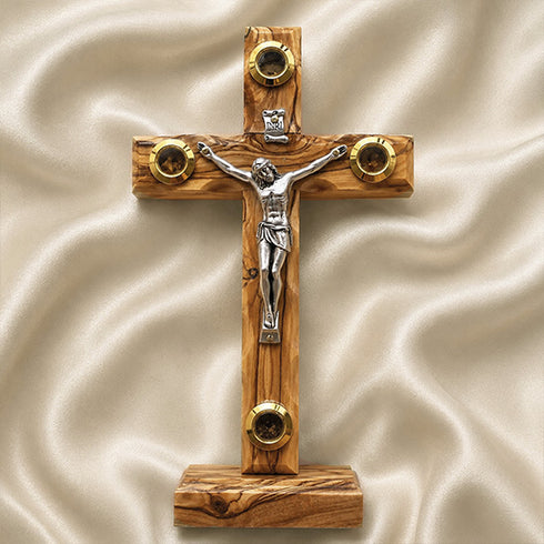 Wooden latin cross with a silver figure on a beige fabric background