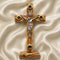 Wooden latin cross with a silver figure on a beige fabric background