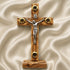 Wooden latin cross with a silver figure on a beige fabric background