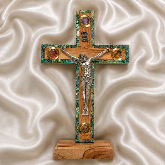 Small latin standing cross with crucifix, mother of pearl inlay and Four Elements, on a white cloth.
