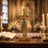Decorative cross with Jesus on the cross in a church setting with candles and an open book.