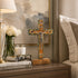 Decorative cross on a nightstand with books, glasses, and flowers.