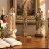 Religious statues and cross on a wooden table with a painting in the background