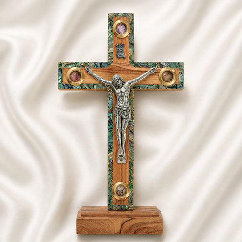 Wooden cross with a figurine of Jesus on a white fabric background