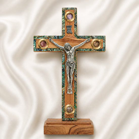 Wooden cross with a figurine of Jesus on a white fabric background