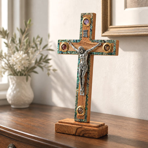 Wooden cross with a corpus on a wooden stand in a room setting.