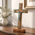 Wooden cross with a corpus on a wooden stand in a room setting.