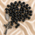 A black lava stone rosary with silver-tone metal links, a Miraculous Medal pendant, and a crucifix.