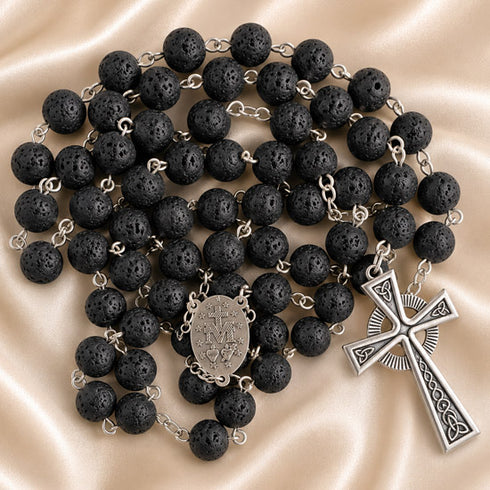 A black lava stone rosary with silver chain links, a round medallion and a detailed celtic cross pendant.