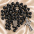 A black lava stone rosary with silver chain links, a round medallion and a detailed celtic cross pendant.