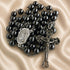 Hematite bead rosary laid flat with oval devotional medal and ornate crucifix