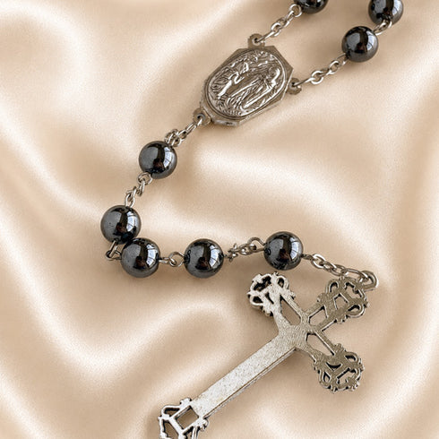 Hematite bead rosary close-up of oval Our Lady medal and linked dark beads