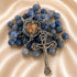 A rosary with round blue beads, a silver-tone crucifix, a central heart-shaped medal with a religious image, on a beige fabric background.