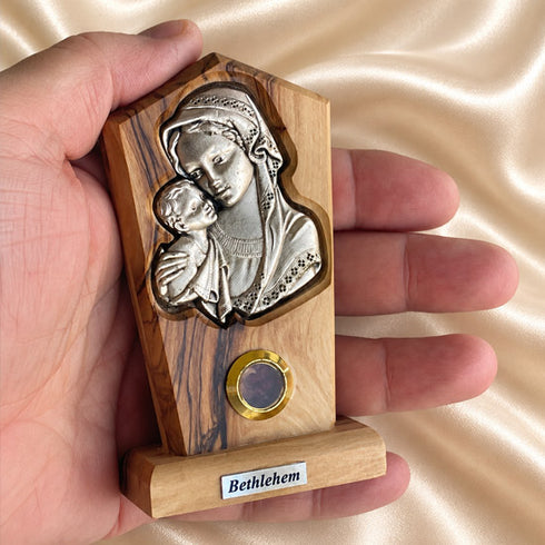 Hand holding a Madonna and Child olive wood plaque, showing its small size and natural bark edge