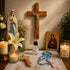 A religious tabletop featuring a wooden crucifix on the wall, a Virgin Mary statue, a Holy Water bottle, blue bead rosary, candles.