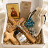 A religious gift set in a white box with a wooden cross, a bottle of holy water, a blue beaded rosary and a certificate